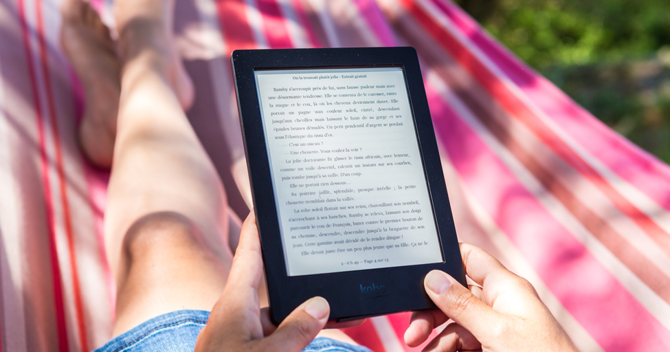 person reading an ebook outside on a picnic blanket