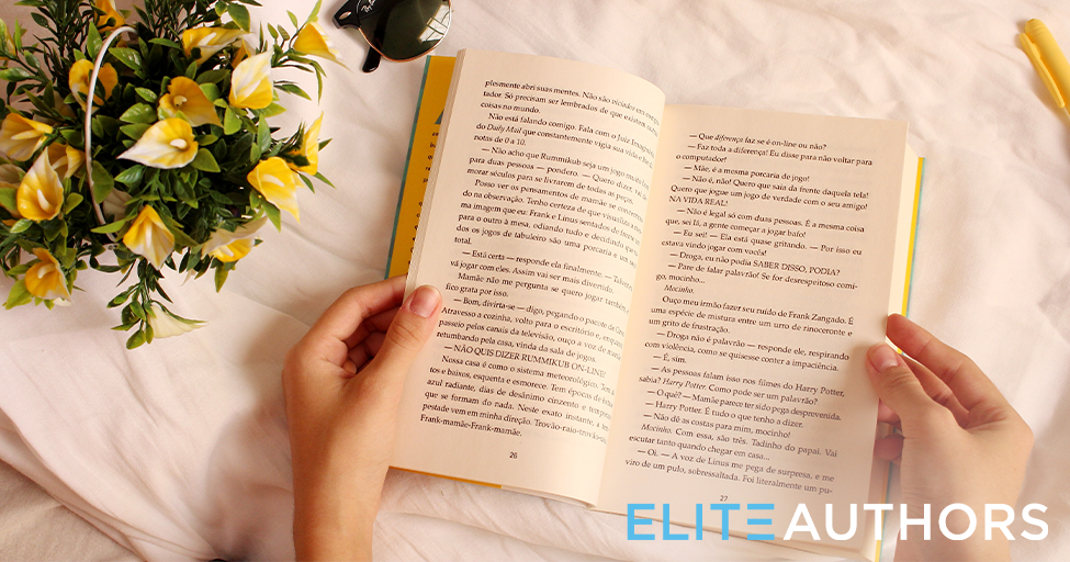 hands opening a book with flowers nearby