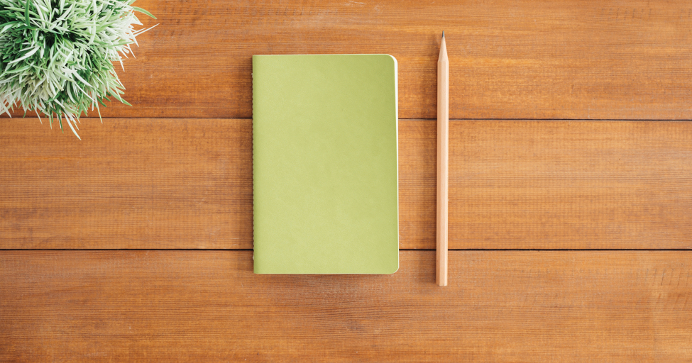 a green notebook and a pencil on a table