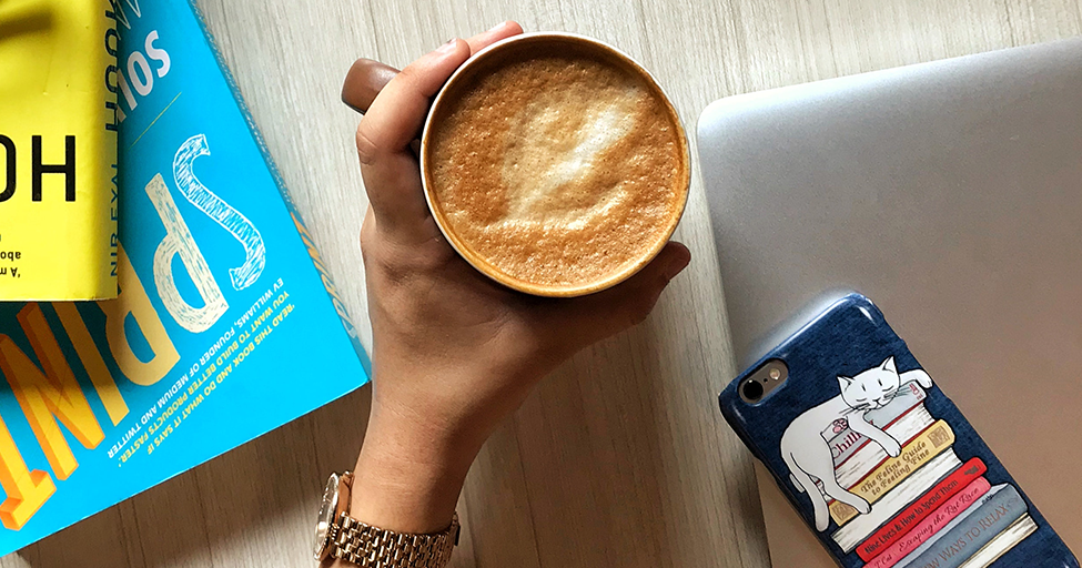 mug of a drink by some books, a phone, and a laptop