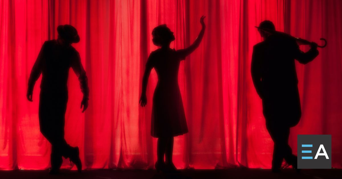 Three dark silhouettes of people in front of a red curtain