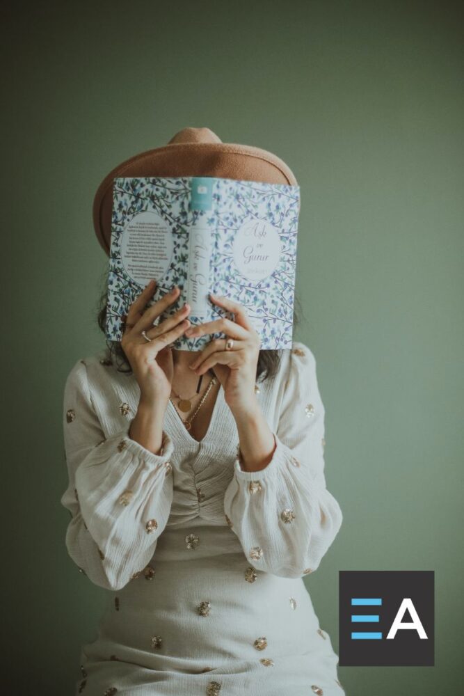 A person whose face is covered by a book