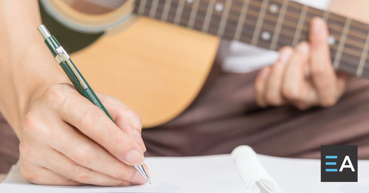 A person with a guitar writing in a notebook