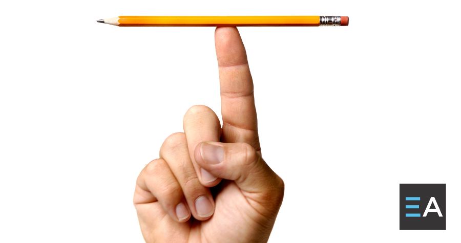 A person balancing a yellow pencil on the tip of their finger