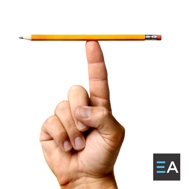 A person balancing a yellow pencil on the tip of their finger