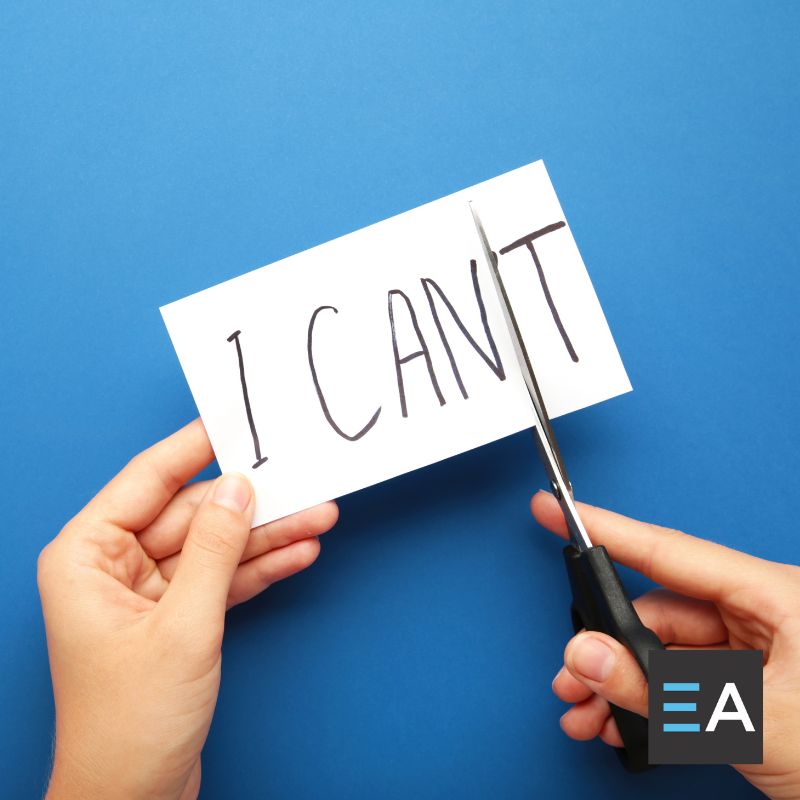 A card with the words "I can't" written on it; a person is using scissors to cut off the T