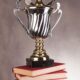 A golden trophy with glasses on it atop a stack of books