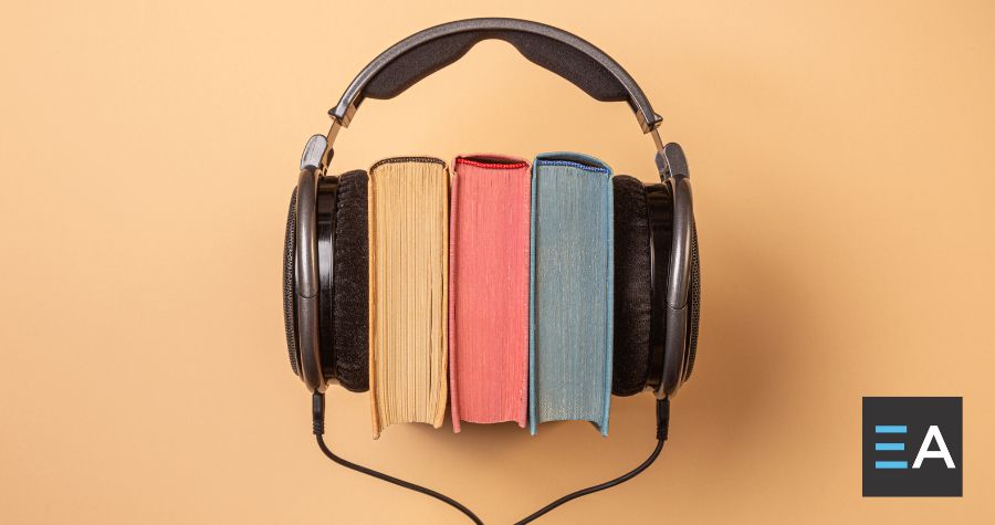 A pair of over ear headphones placed around three colorful books