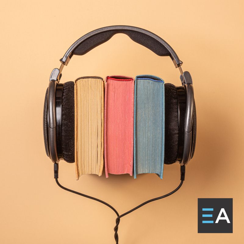 A pair of over ear headphones placed around three colorful books