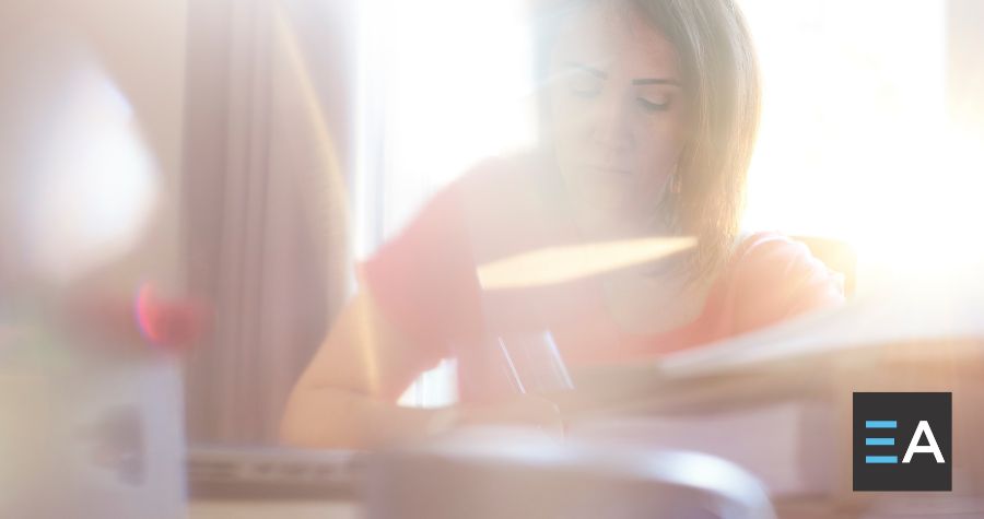 A person obscured by lens flare working at a desk
