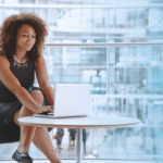 A person in a business environment types on a laptop.