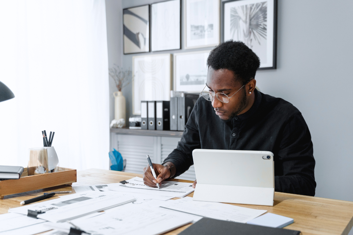 A business person takes notes from a tablet at a cluttered desk