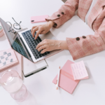 An author uses a laptop and takes notes on a white table
