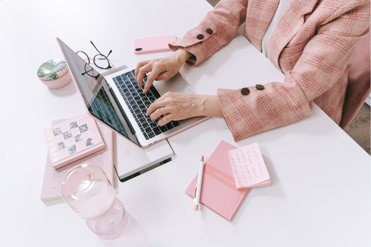 An author uses a laptop and takes notes on a white table