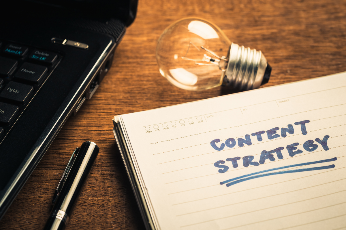 The words "content strategy" on a notebook next to a laptop