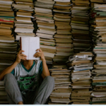 A reader sits in front of a stack of books