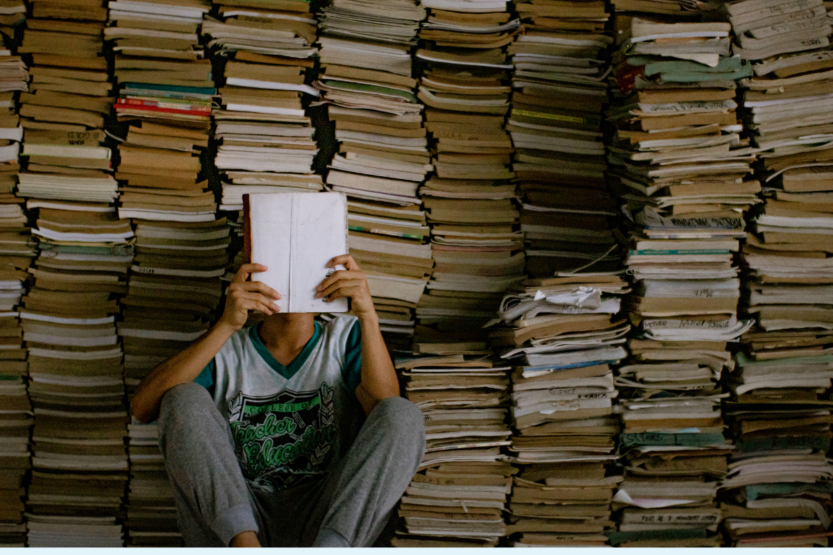 A reader sits in front of a stack of books