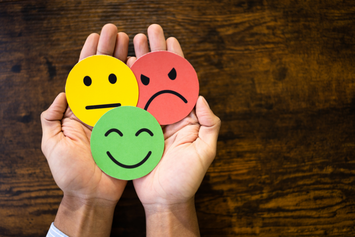 A person's holds three faces; happy, neutral, and angry; in cupped hands