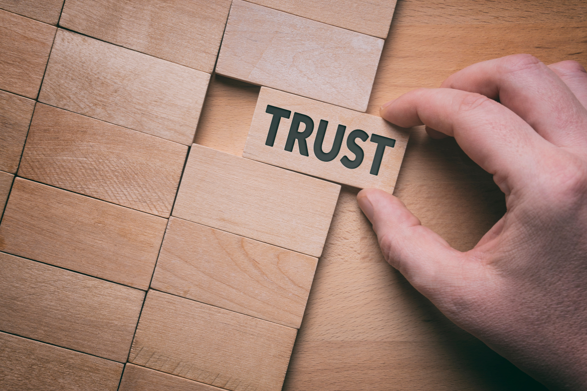 A person places the word trust on a wooden block into a stack of plain blocks