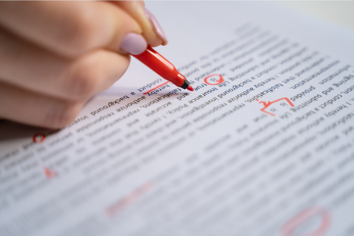 A person makes red marks on a printed manuscript
