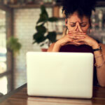 A person stresses over what they see on a laptop