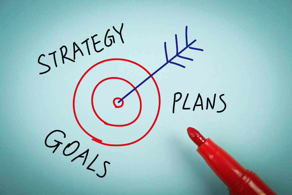 A target drawn with a red marker has the words strategy, plans, and goals around it