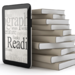 A stack of printed books next to an ereader