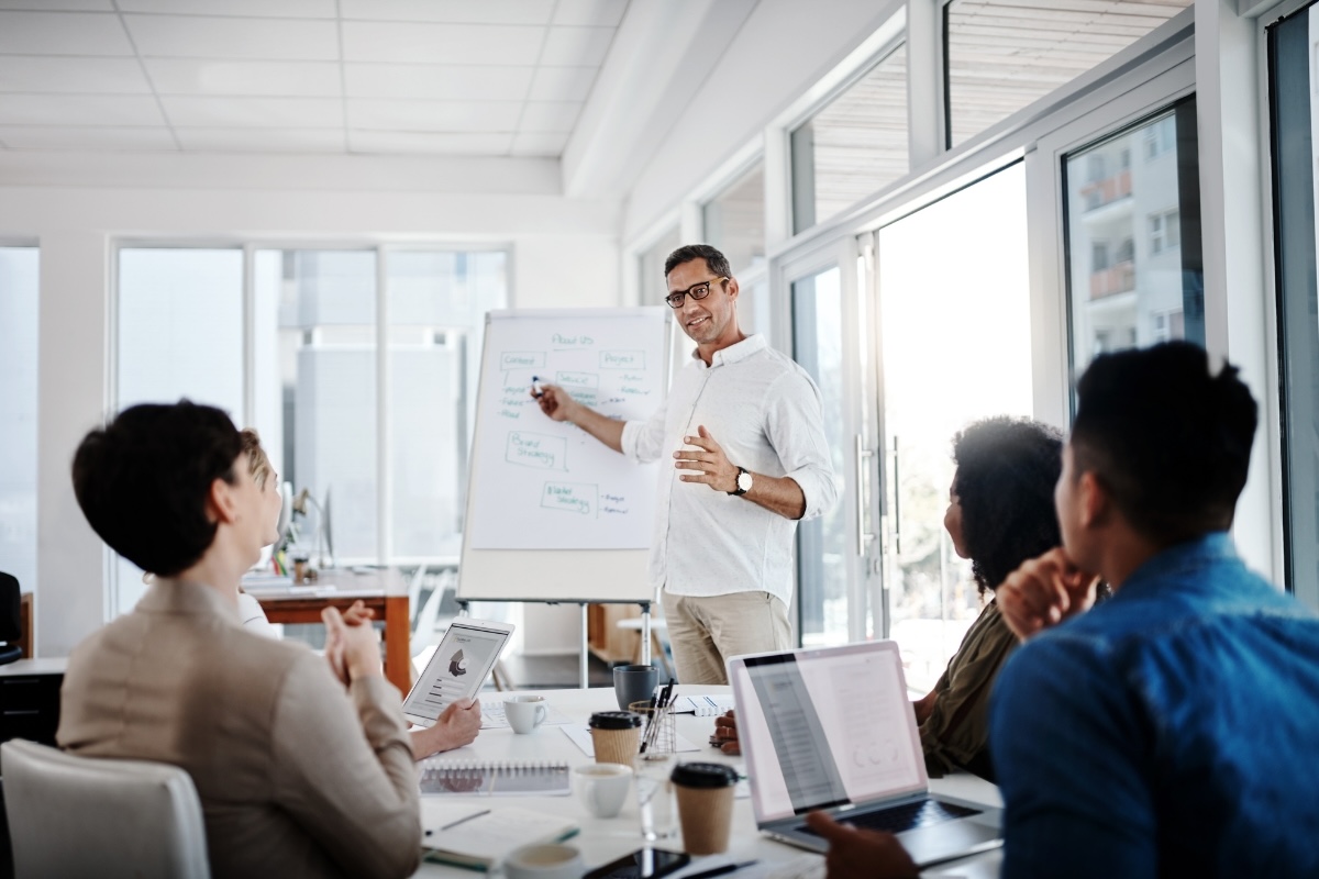 A presenter uses a whiteboard to share a business book idea with a group of people