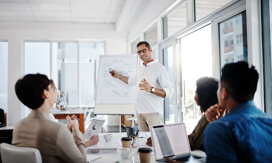 A presenter uses a whiteboard to share a business book idea with a group of people