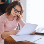 A business writer overcomes writer's block by taking notes on sheets of paper