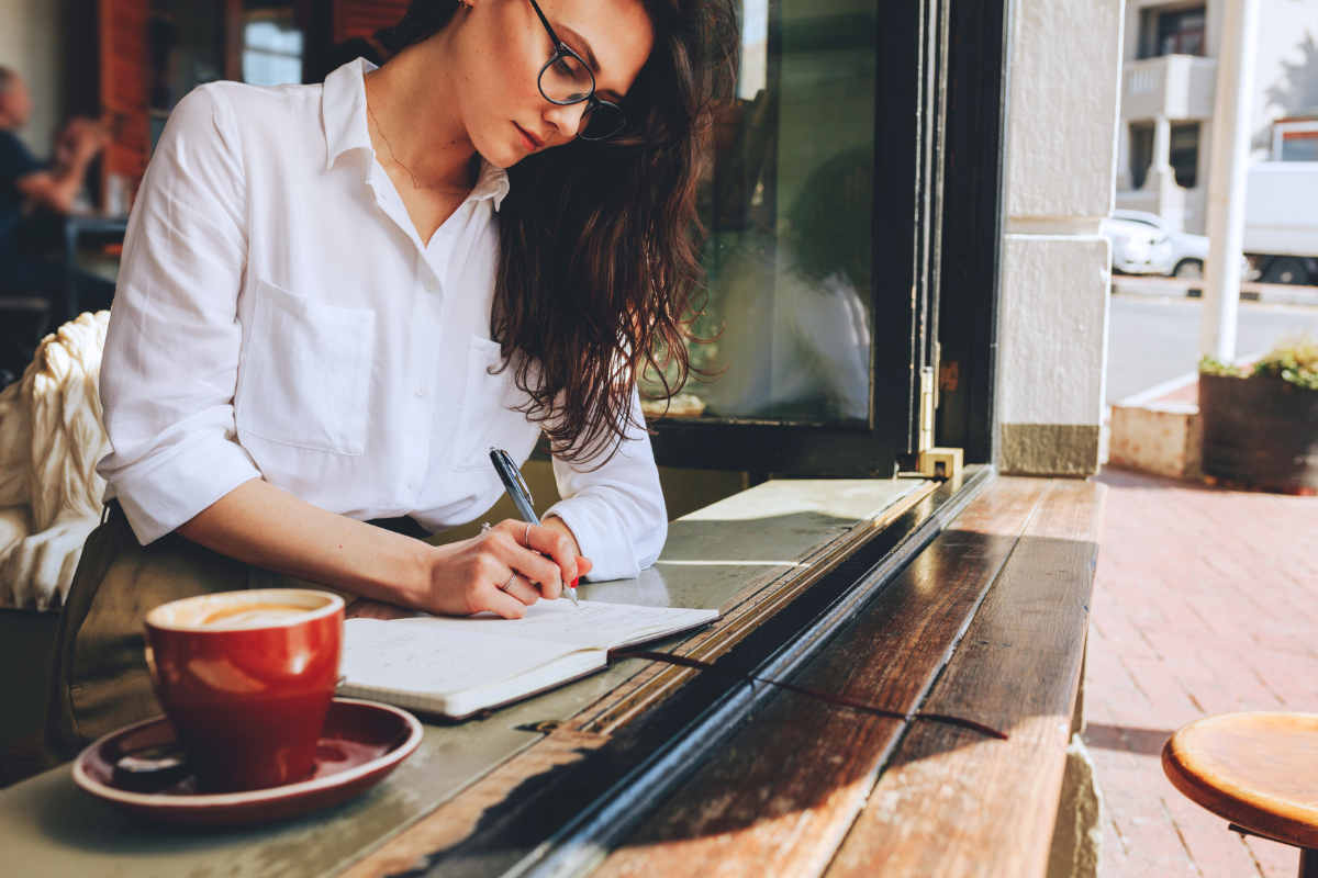 A business writer outlines their book on a notebook in a cafe