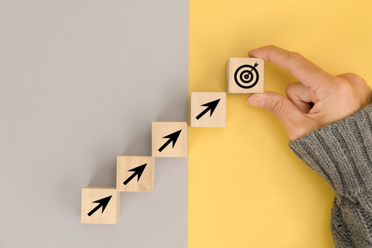 Four wooden blocks with arrows on them point toward a target