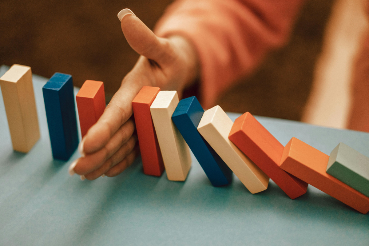 A person prevents a line of wooden blocks from knocking over