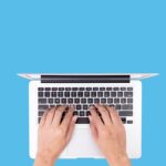 A person types a well-written book description on a laptop