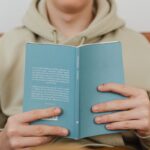 A person reads a book with the back cover visible