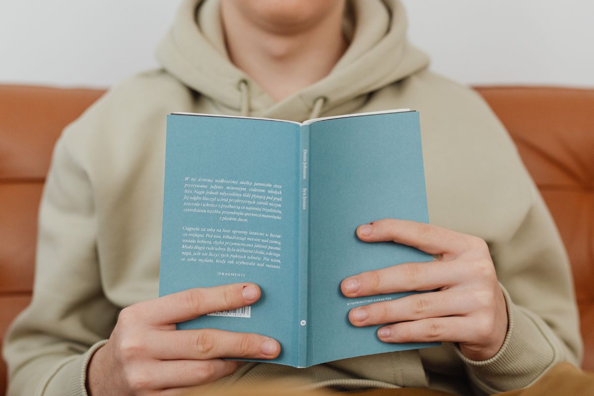 A person reads a book with the back cover visible