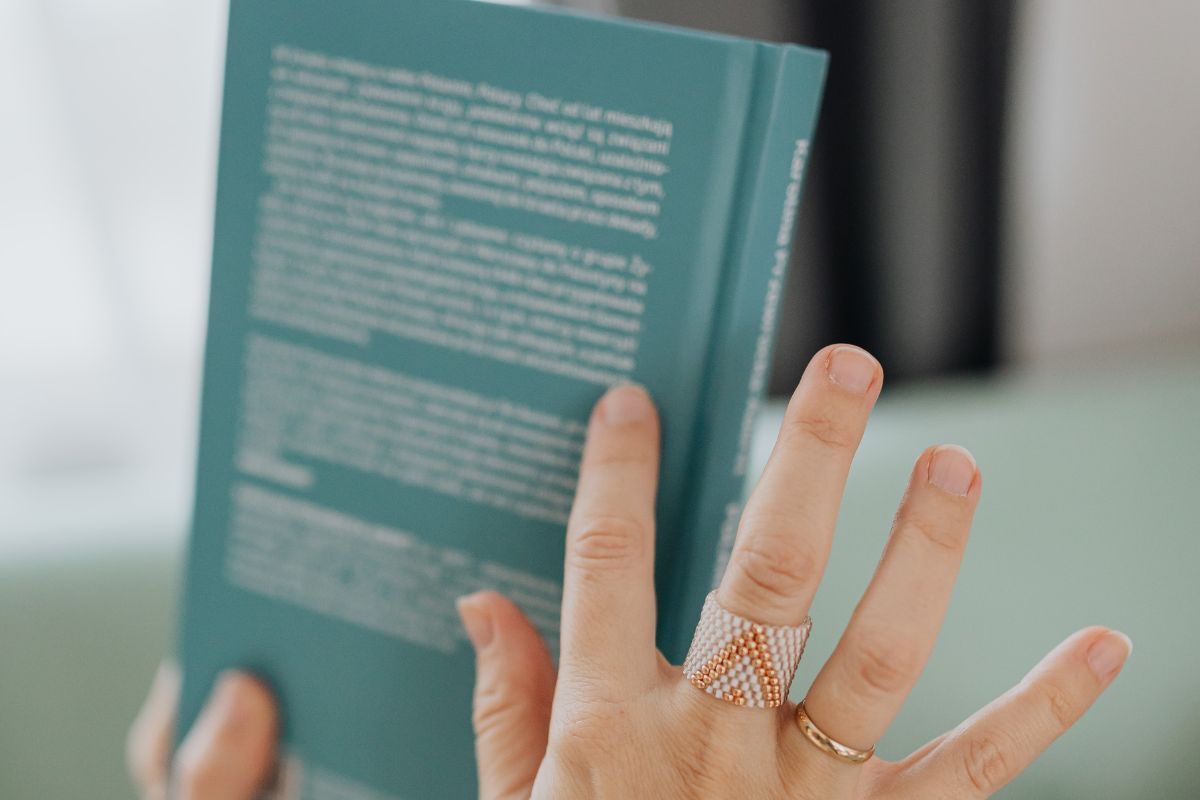 A person holds a book with the back cover visible