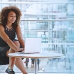 A person in a business environment types on a laptop.