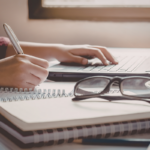 A writer uses a pen and a laptop