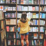 A person selects a book from full shelves in a bookstore