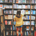 A person selects a book from full shelves in a bookstore