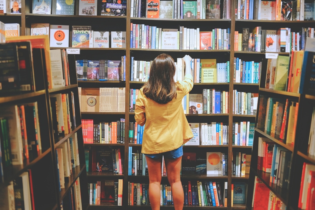 A person selects a book from full shelves in a bookstore