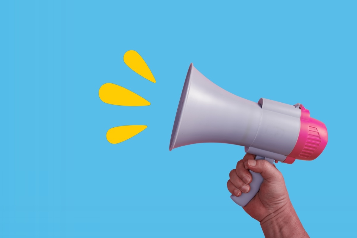 A person holds a megaphone emitting sound waves