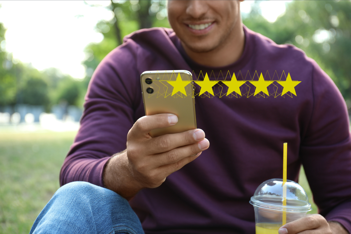 A person smiles at a smartphone that has five stars next to it