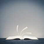 A self-published book lies open on a flat surface, its pages turning in the wind