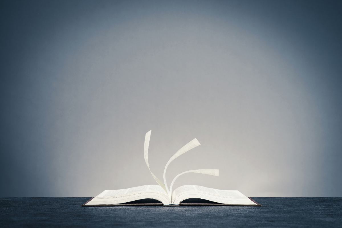 A self-published book lies open on a flat surface, its pages turning in the wind