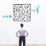 A person faces a wall with a drawing of a maze on it.