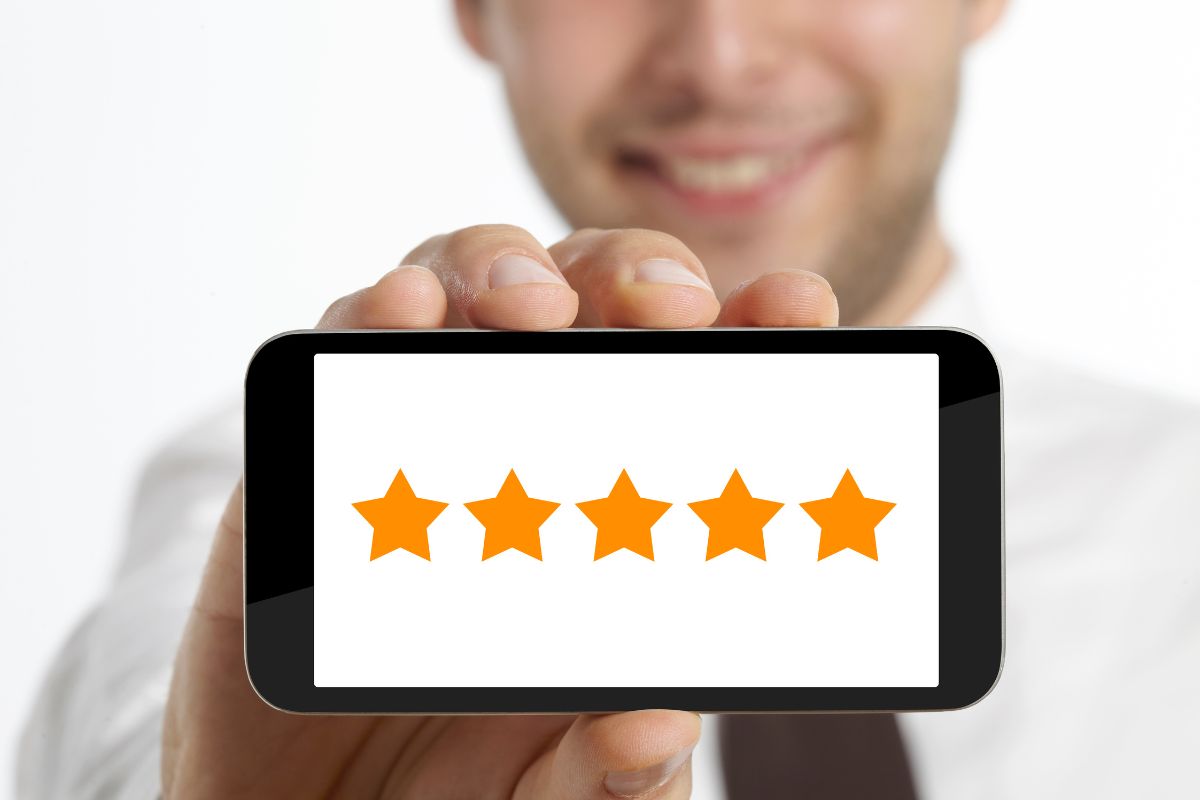 A person holds up their phone, which displays five yellow stars