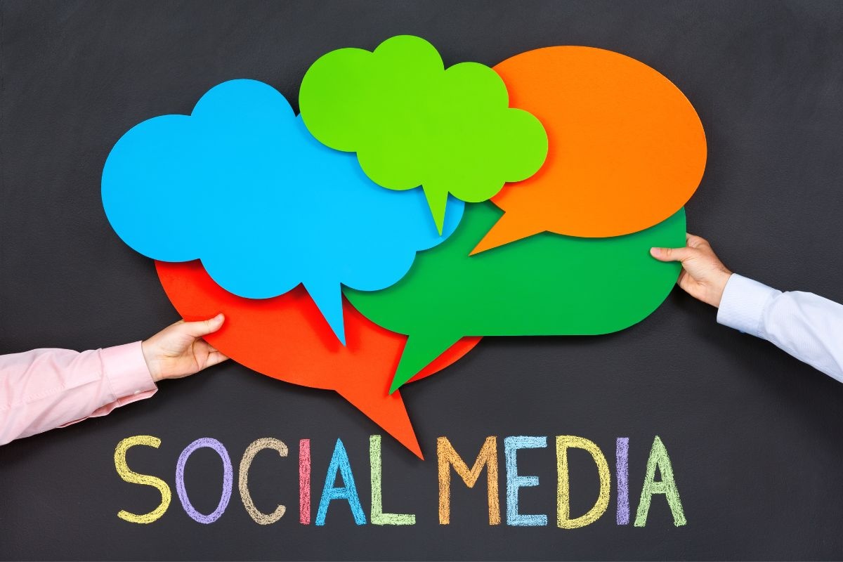 Two people hold colorful cutouts of speech bubbles above the words social media
