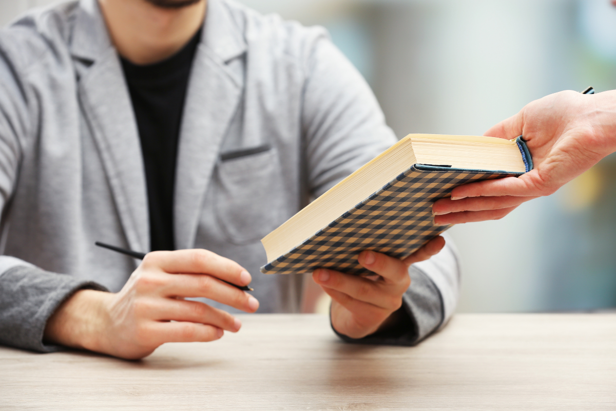 A person hands a book to another